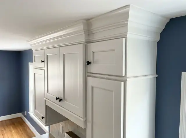 Illustration of white painted kitchen cabinets topped with stepped crown molding