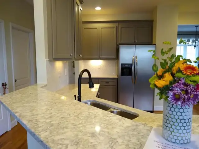 Kitchen with taupe painted cabinets, light granite countertops, undermount sink and black faucet